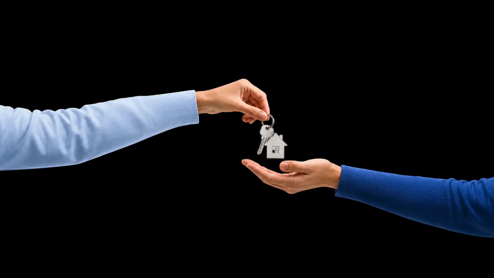 Übergabe eines Wohnungsschlüssels mit Haus-Anhänger von einer Hand in eine andere